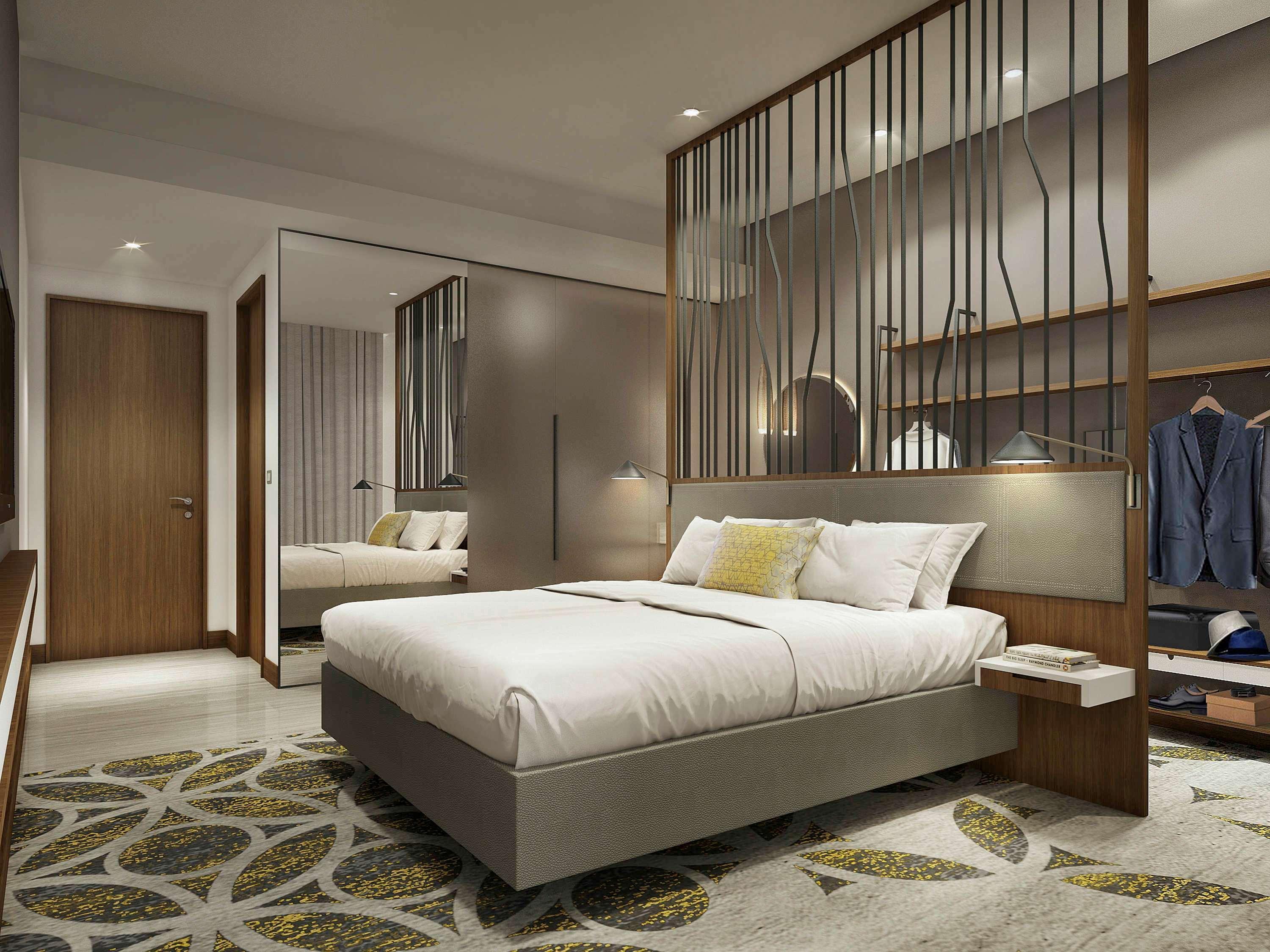 Grand Mercure Dubai City Hotel Exterior photo The photo shows a modern hotel room featuring a neatly made bed with white linens and a decorative pillow. The room has a stylish wooden partition that separates the sleeping area from the rest of the space. There are bedside tables on either side of